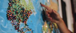 A world map with many pins stuck in it